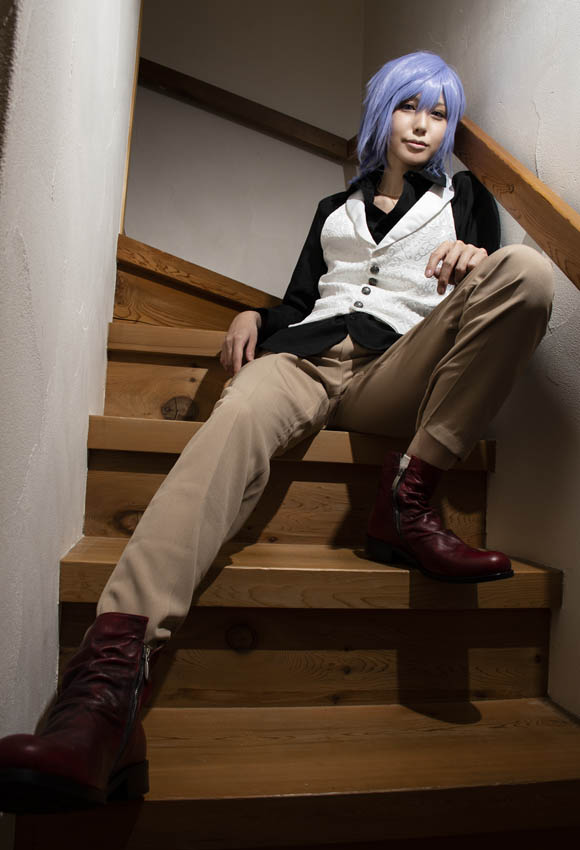 階段に座る男装の女性の、長い脚が強調された写真。