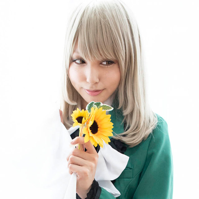 窓からの自然光を活かした、花を手に持って窓際に座る女性の写真。