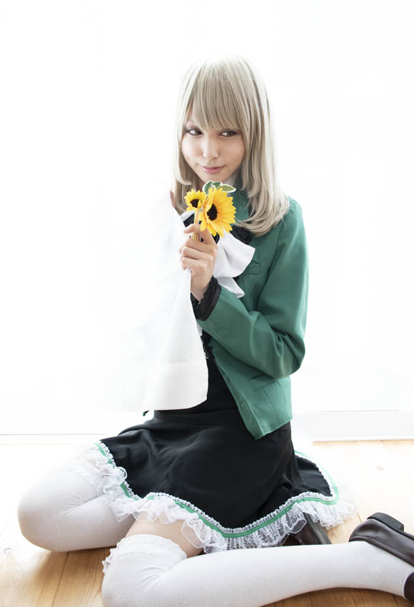 窓からの自然光を活かした、花を手に持って窓際に座る女性の写真。