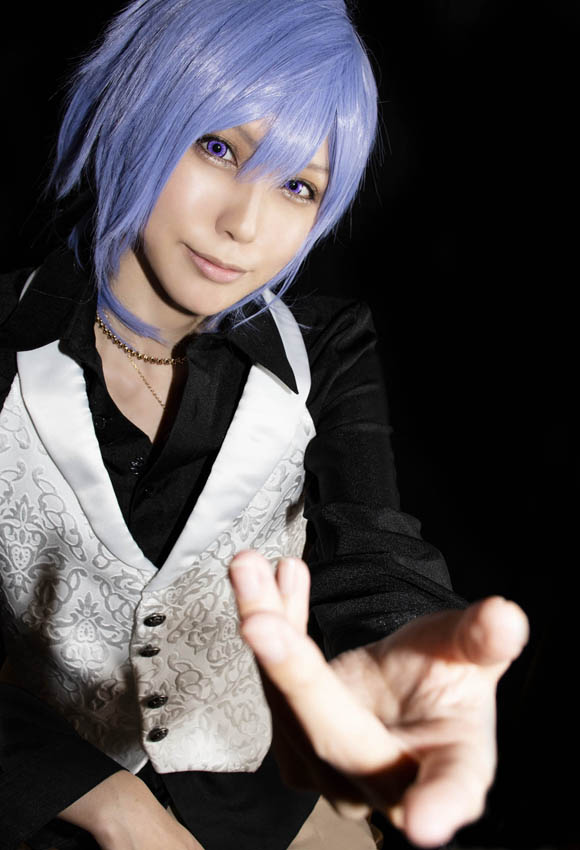 こちらに向かって手を伸ばし、何かを語りかけるような男装の女性の写真。