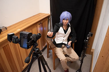 こちらに向かって手を伸ばし、何かを語りかけるような男装の女性の写真の撮影風景。