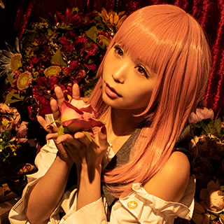 アンティーク調の部屋の中で、薔薇を手にして座り込む女性の写真。