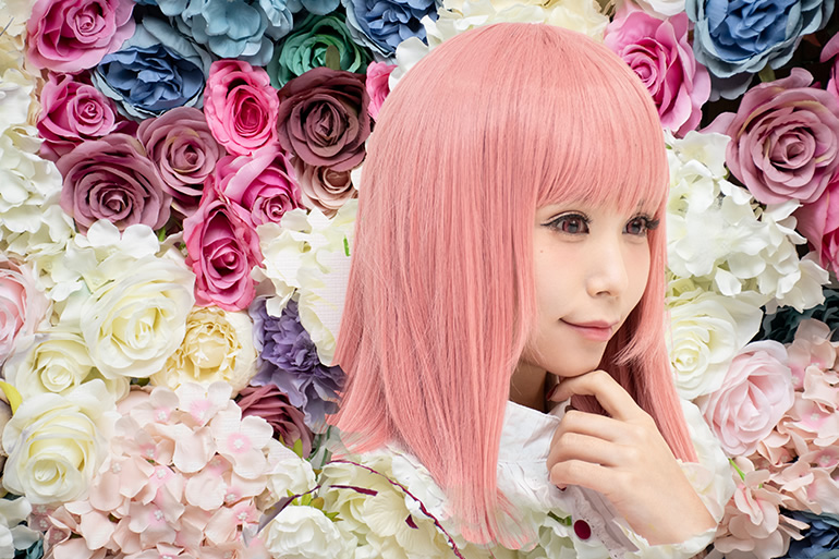 色とりどりの花の中で微笑む女性の写真。詳細は本文内。