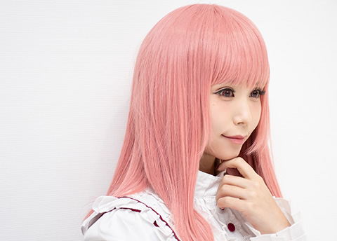 白い壁を背に微笑む女性の写真。