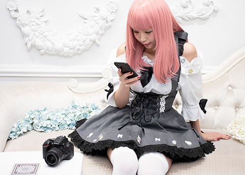 ソファに座り、スマートフォンで写真を見る女性の写真。