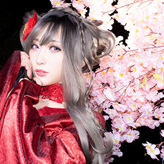 夜桜を背景に、こちらを見つめる赤い着物の女性の写真。