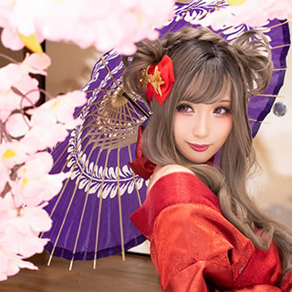 桜の木の下で和傘を指して振り返る赤い着物の女性の写真。