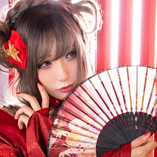 扇子を手に、赤い格子戸の傍らでポーズを取る赤い着物の女性の写真。