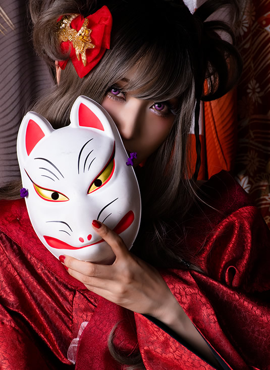狐のお面で口元を隠してこちらを見つめる、赤い着物の女性の写真。