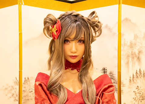 屏風の前に座り、こちらを見つめる赤い着物の女性の写真（スピードライトを使用しない例）。