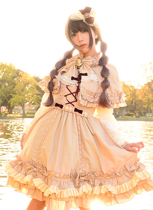 川沿いに立ち、真正面を向いてポーズを決める女性の写真。