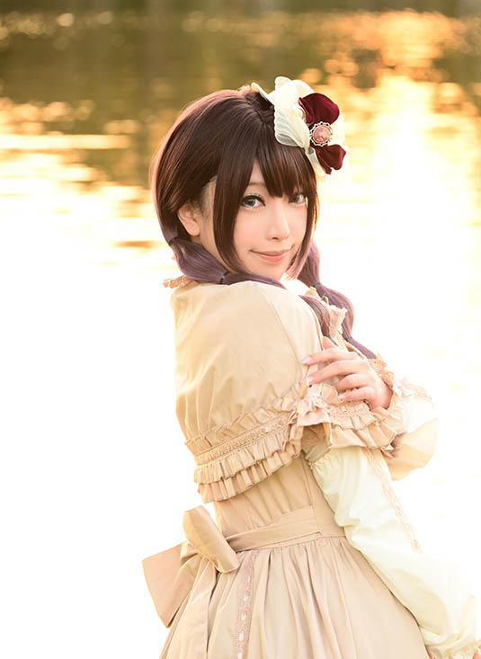 夕焼けの川沿いでこちらに視線を投げる女性の写真。