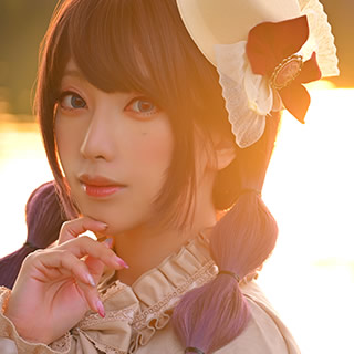 夕暮れの水辺でアンニュイな表情を見せる女性の写真。