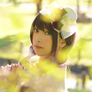 前ボケした小枝越しにこちらを見つめる女性の写真。