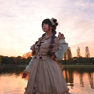 夕景をバックに川べりにたたずむ女性の写真。