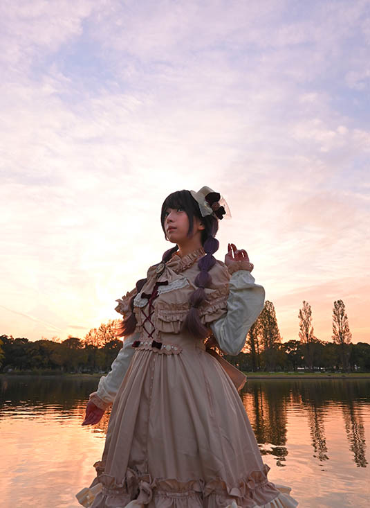 夕景をバックに川べりにたたずむ女性の写真。