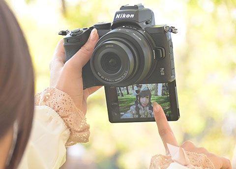 「自分撮り」のため、カメラの画面モニターをタッチする女性の写真。