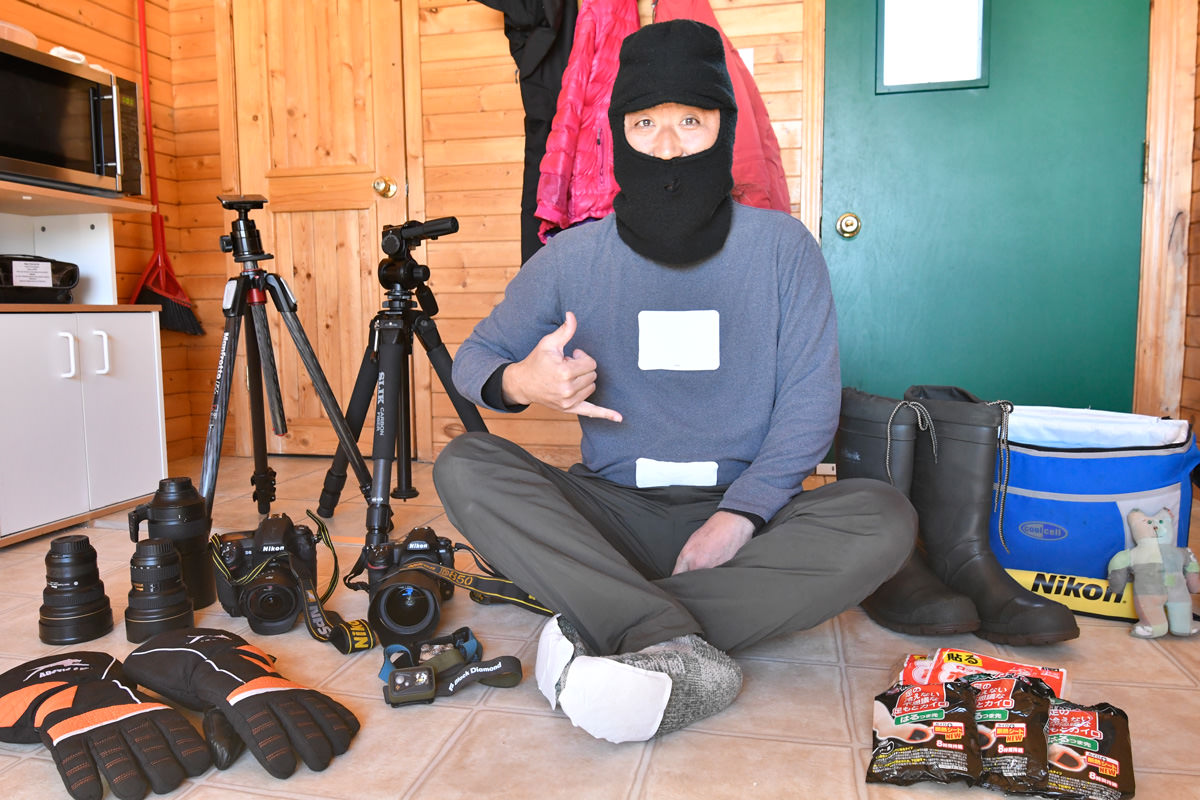 オーロラの撮影準備をする僕。何時間も極寒の中で耐える必要があるため、からだのあちこちに使い捨てカイロを貼り、顔をスッポリと覆う防寒帽をかぶる。タイムラプス映像のためのD850と静止画撮影用のD5、2組のカメラと三脚を用意した。