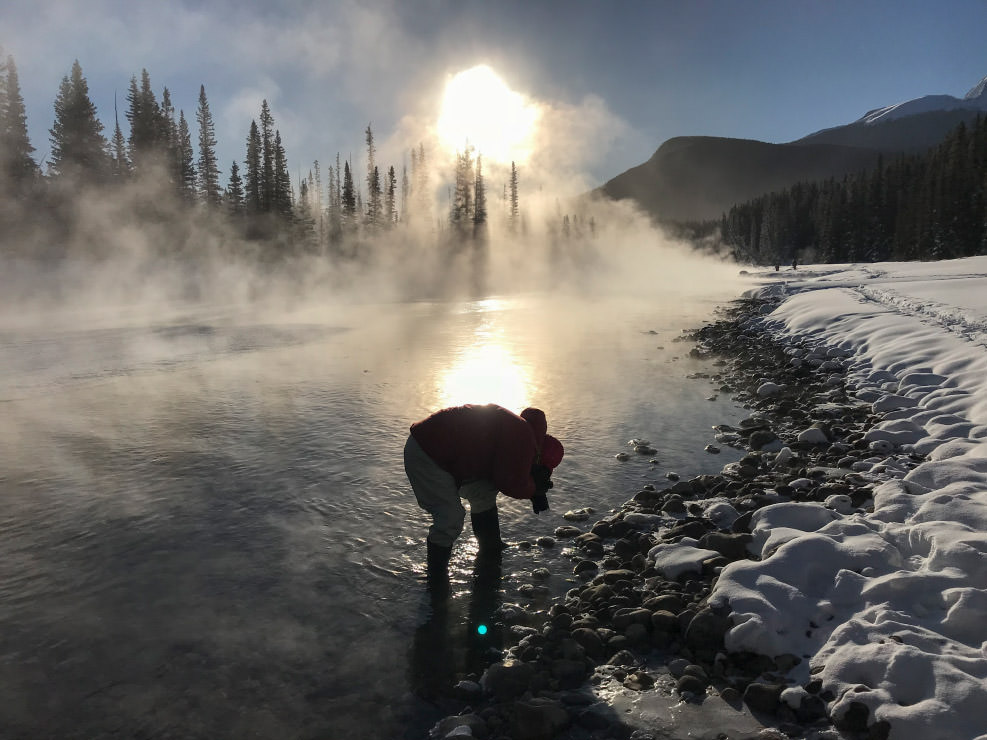 マイナス32度の朝、あまりの寒さに川面から湯気が立ち昇る。長靴で川に入って岩に付いた結晶を狙う。「結晶」（4枚組左下）の撮影風景。