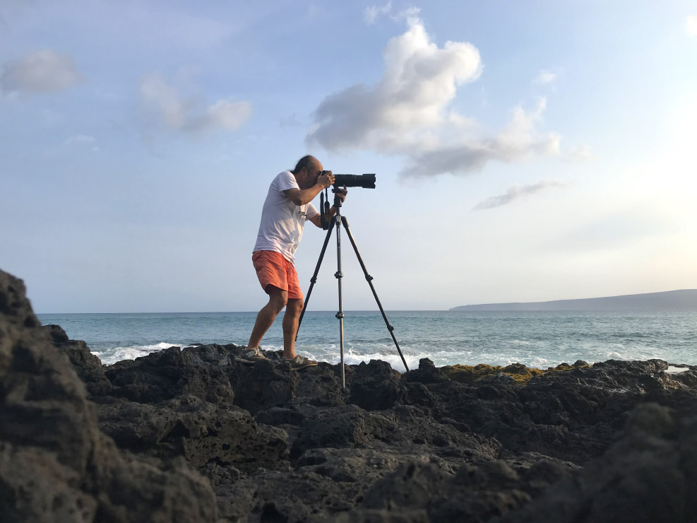 海辺で、三脚にカメラを載せて波の動きを撮影する。
