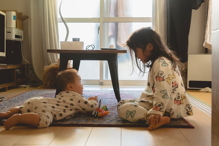 女の子が赤ちゃんと見つめ合っている写真