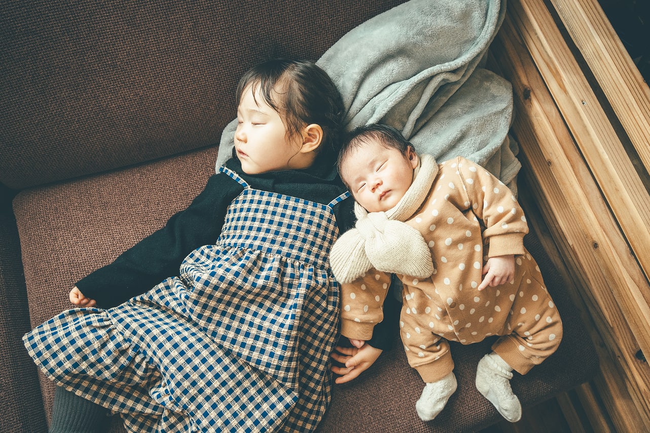 女の子と赤ちゃんが一緒に寝ている写真