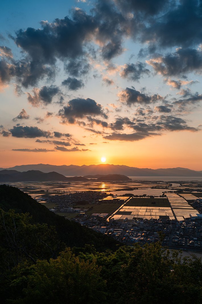 夕焼けに染まる湖畔の街と山並み